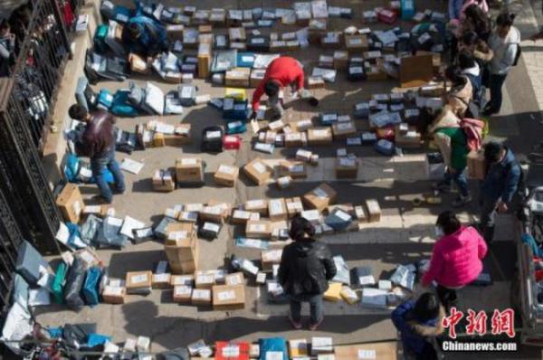 资料图：工作人员忙着分拣满地的快递。 武俊杰 摄