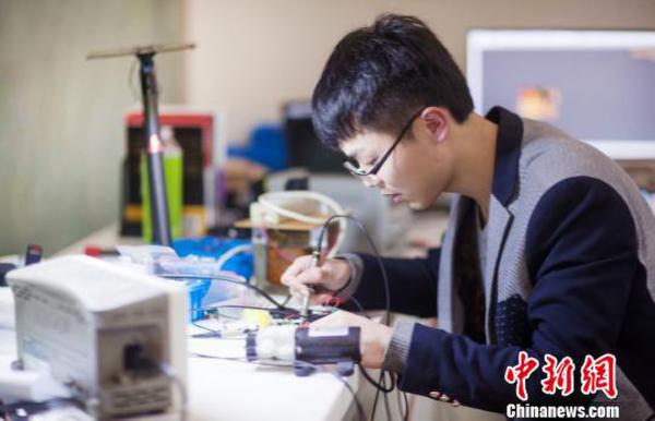 图为虞昊迪正在调试一架无人机的电池平衡充 陈位权 摄