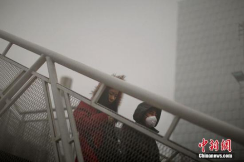 12月4日，戴着口罩的行人从天桥上走过。天津市气象台当日7时发布大雾橙色预警信号，天津大部分地区笼罩在大雾中，局部地区能见度低于200米。 <a target=