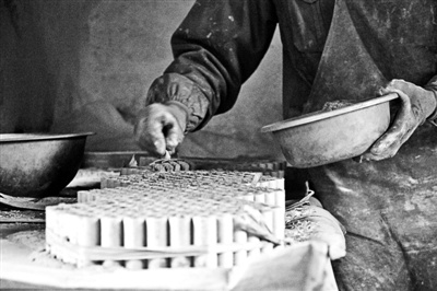 在浏阳一个花炮车间，技师小心地将药珠装进筒管