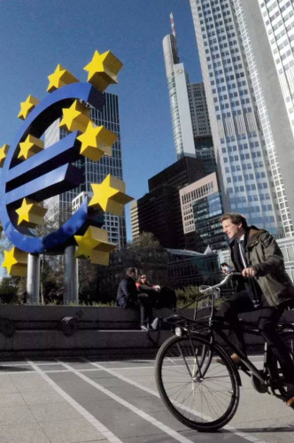 行人经过法兰克福“欧元塔”大厦前的巨型欧元雕塑。中新社记者 彭大伟 摄