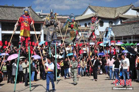 资料图 1月30日，表演者在他人辅助下来回走动。当日，云南石屏县街头，来自当地龙武镇的高跷队伍亮相，引众多市民围观。 中新社记者 刘冉阳 摄