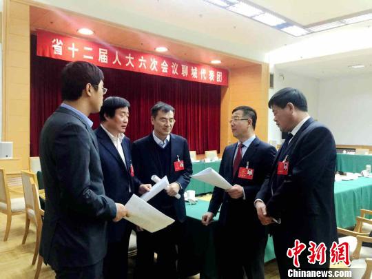 山东省人大代表秦玉峰与参会代表一起讨论刚刚“出炉”的《山东省政府工作报告》。　李欣 摄
