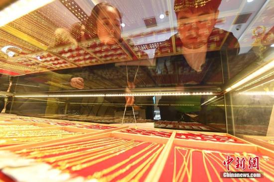 资料图：民众挑选黄金首饰。 中新社记者 韦亮 摄