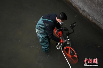 资料图：一辆共享单车被扔进成都锦江，工作人员冒着寒冬下水将其打捞上岸。张浪 摄