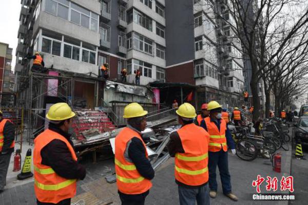 资料图：2月21日，北京市西城区白纸坊西街上，聚集了不少工程车和执法人员，随着对大清花饭店门前避风格的拆除，拉开了白纸坊地区2017年“开墙打洞”整治行动的序幕。由于历史原因白纸坊西街南侧不少居民楼底墒形成了大量违法建设。金硕 摄