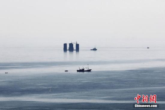 3月19日上午，山东省青岛西海岸新区灵山湾海域，正在海边散步的市民发现，在灵山岛附近，海平面出现几座高楼状的物体，原本空荡的海平面突然出现这样的奇景，多数人猜测这是“海市蜃楼”。中新社发 王培珂 摄 图片来源：CNSPHOTO