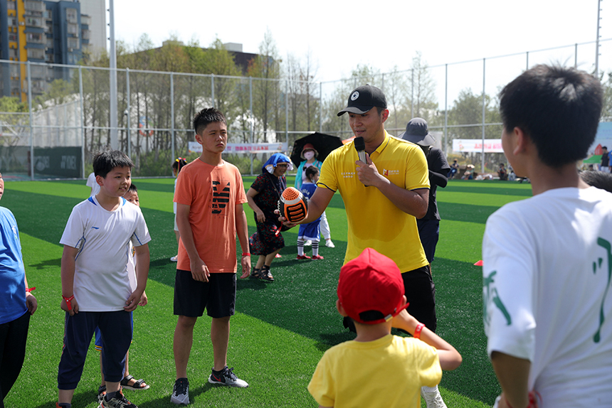 腰旗橄榄球教练正在教孩子们如何传球。 范伟摄